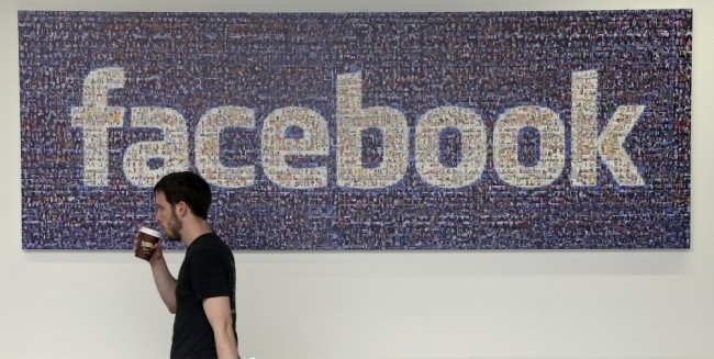 FILE - In this March 15, 2013, file photo, a Facebook employee walks past a sign at Facebook headquarters in Menlo Park, Calif. A Facebook official said the company has found no evidence to back up allegations in a May 9, 2016, report from Gawker's Gizmodo blog that company contractors suppressed stories of interest to conservatives in its Trending section. (AP Photo/Jeff Chiu, File)